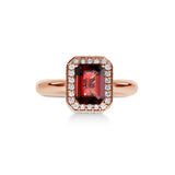 Gros plan du grenat sur la bague Symbole Rosso en or rose, mettant en valeur le halo de diamants.